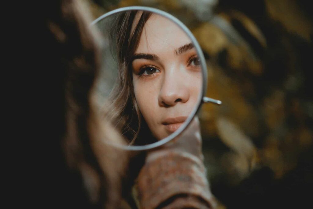 Teen girl looking at her reflection in mirror, symbolizing self-awareness developed through CBT for teen.