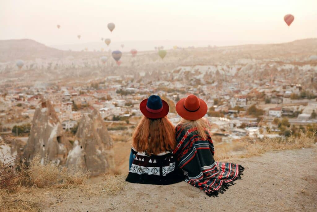 Two women in hats sit on a hill, gaining self-confidence with Cognitive Behavioral Therapy in San Francisco