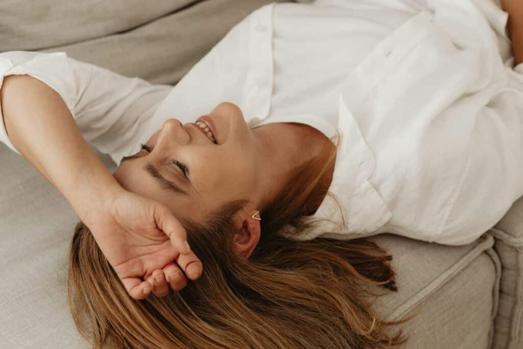 Smiling woman lying on couch, appearing relaxed—reflecting progress with a depression therapist near San Francisco.