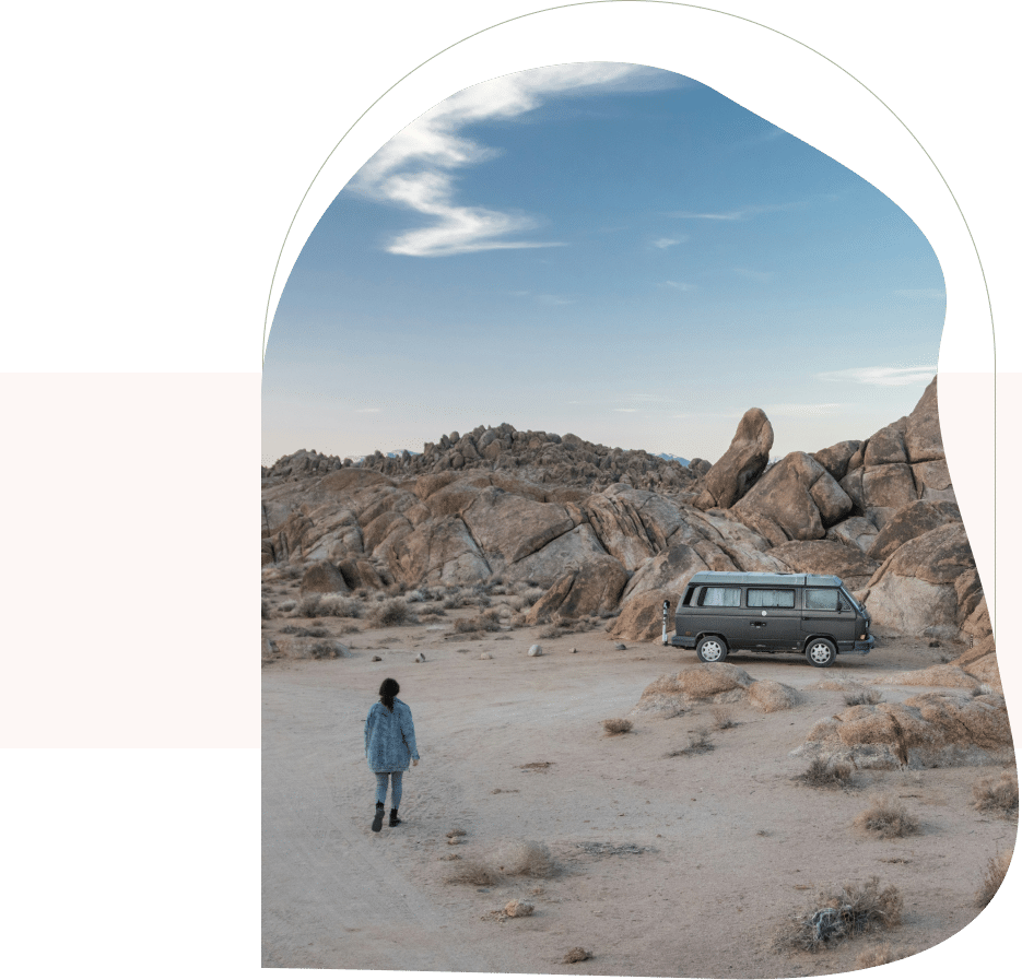 Woman walking in rocky desert with camper van, showing resilience and growth with a CBT therapist in San Francisco.