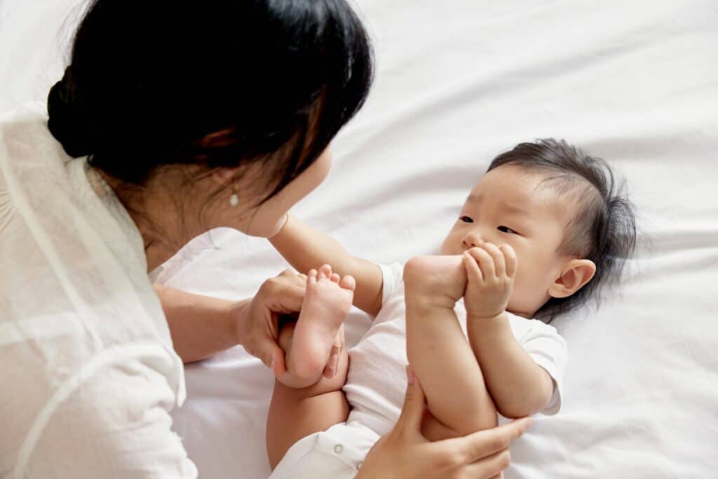 Mother holding and engaging with infant on bed, showing nurturing bond supported by parent therapy in San Francisco.
