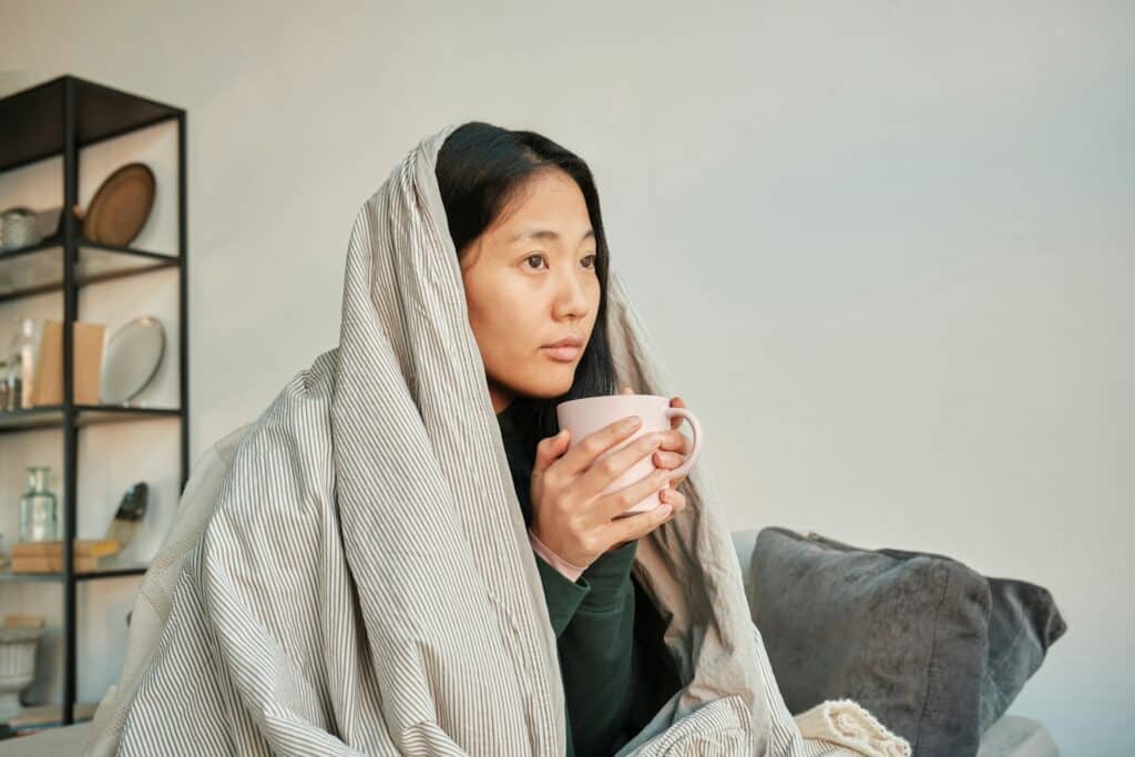 Woman wrapped in blanket, holding a mug, finding clarity and calm through CBT counseling in San Francisco.