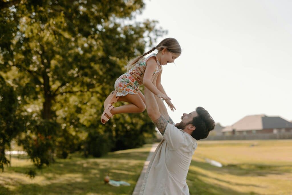 Smiling dad lifts daughter outdoors, reflecting positive change from parent counseling San Francisco.