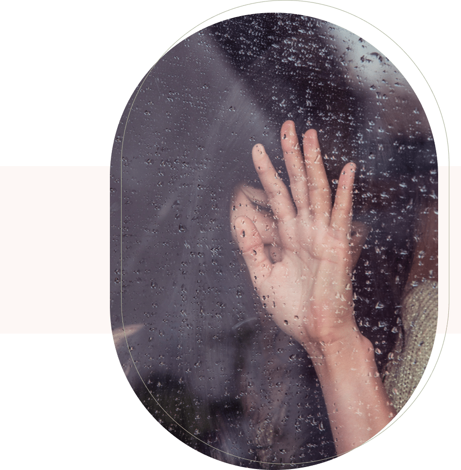 Woman touches rain-covered window, showing emotional struggle supported by a San Francisco therapist’s help.