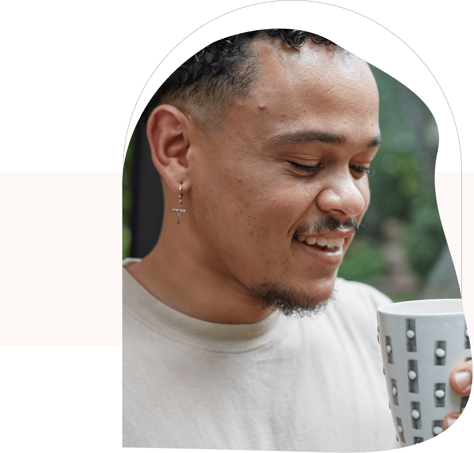 Smiling man holding a mug, reflecting calm and comfort after seeing a therapist for anxiety in San Francisco.